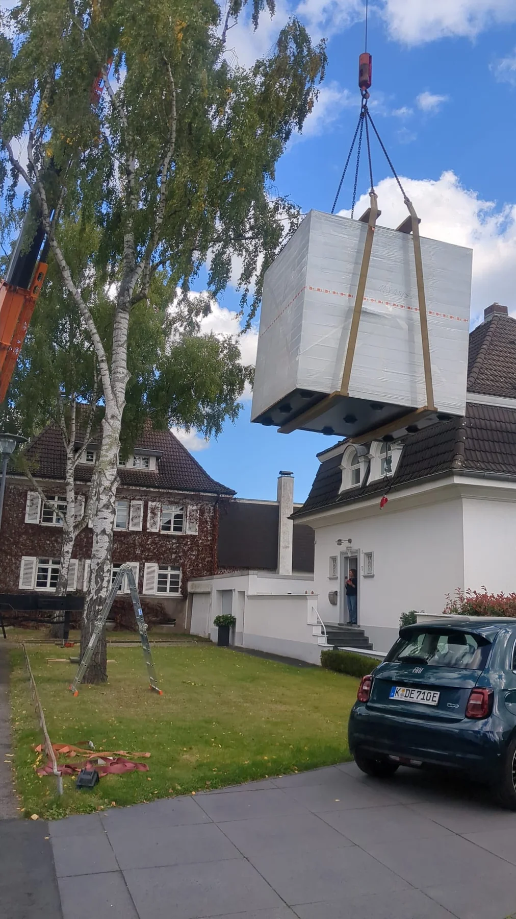 A crane moving a complete wrapped prefabricated unit into a residential garden