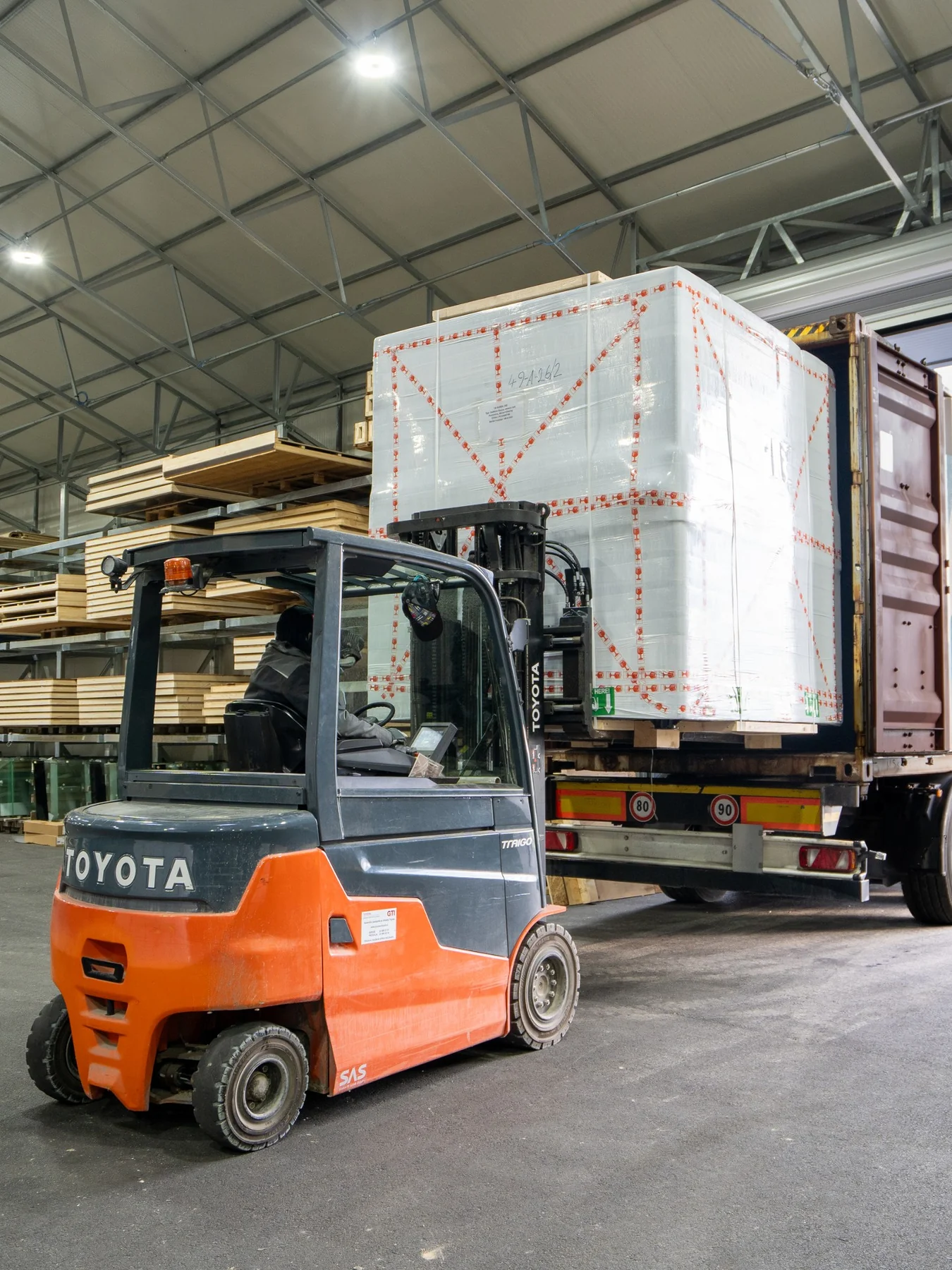 A forklift loading a wrapped prefabricated unit into a shipping container
